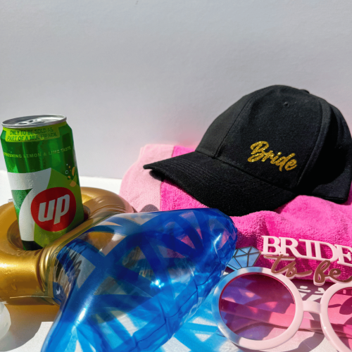 Bride-to-be accessories including black bride cap and pink sunglasses for a destination wedding